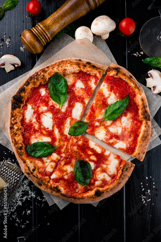 Neapolitan pizza Margherita with mozzarella, tomato sauce, spinach on a thick dough with spices cut into pieces.