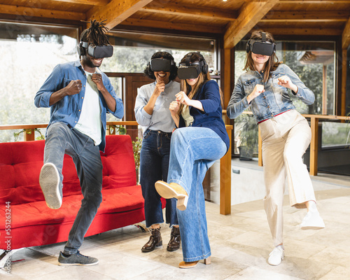 Fototapeta Naklejka Na Ścianę i Meble -  group of young people playing with virtual reality and visor, gamers in action while virtually doing martial arts, new technologies applied in a playful way