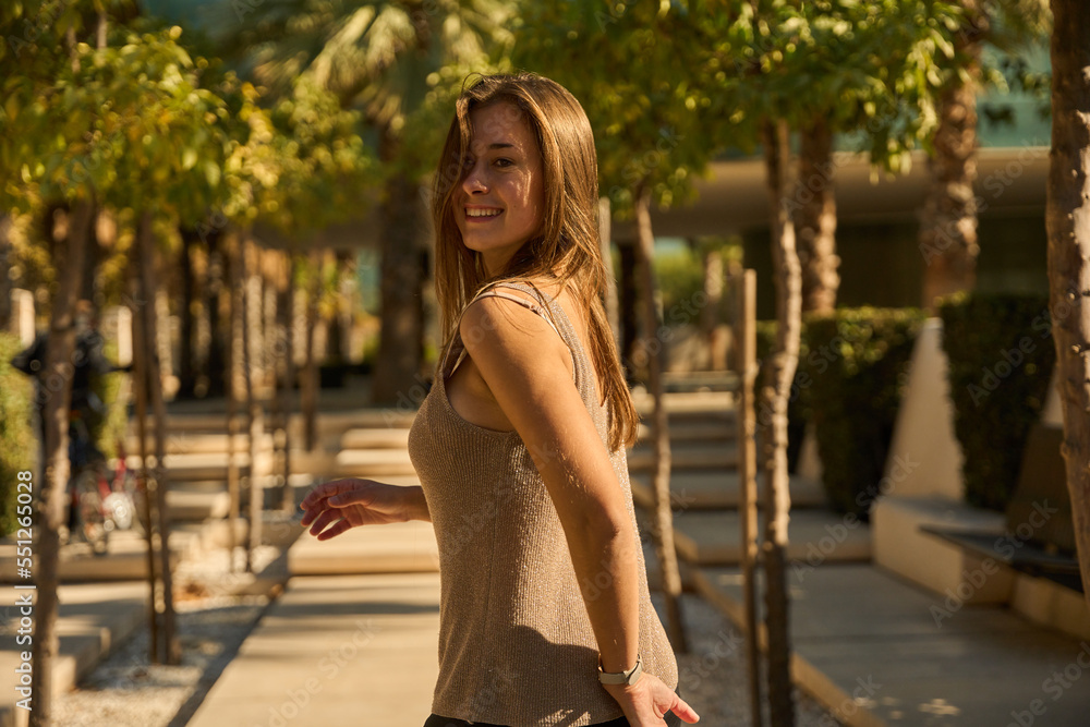 young beautiful woman dancing in a park full of tropical palm trees in a southern European city