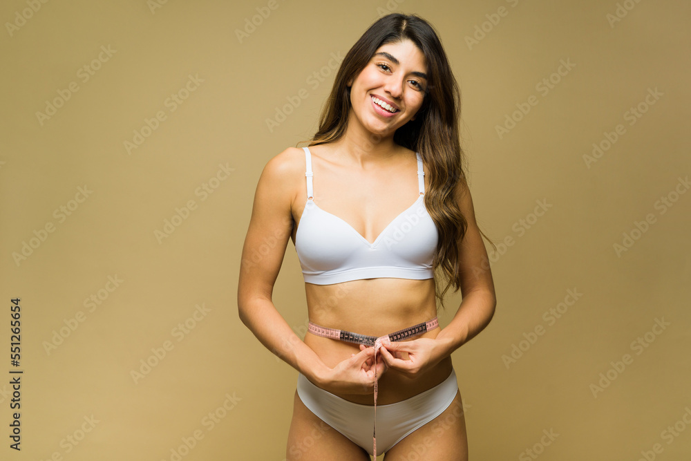 Excited woman on a diet using a measuring tape on her waist Excited woman on a diet using a measuring tape on her waist