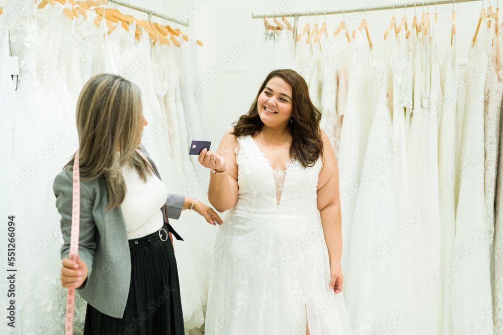 Cheerful fat woman paying with a credit card for her wedding dress