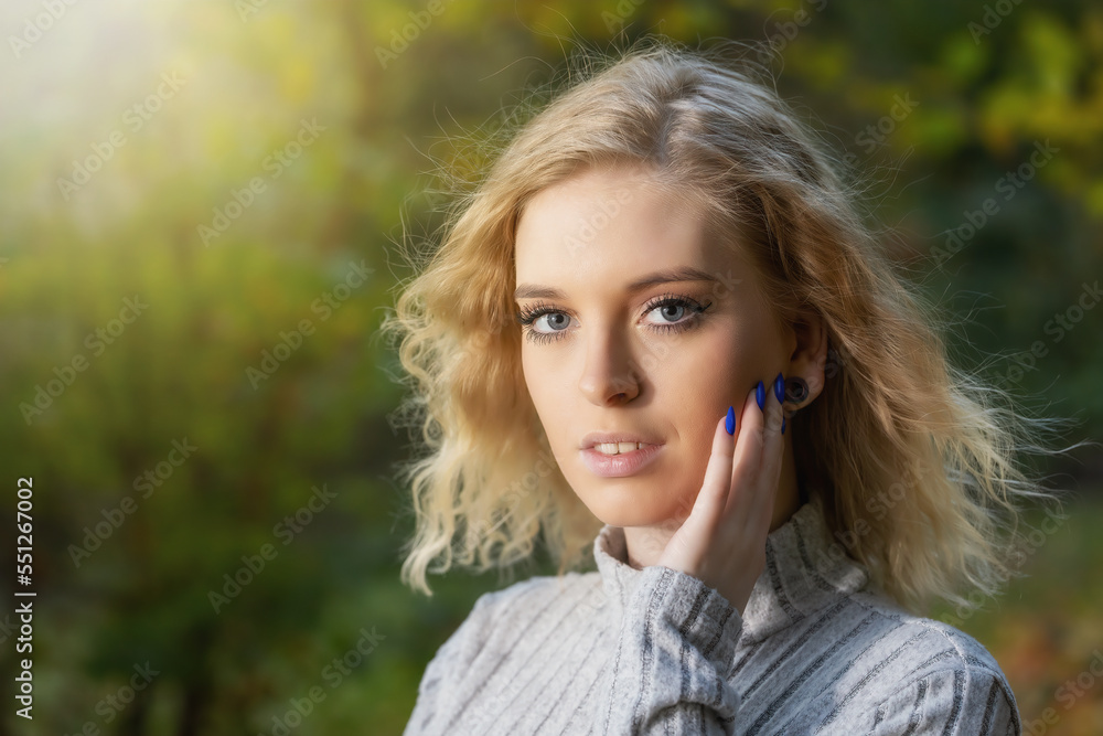 Portrait of attractive young woman posing outdoors in autumn. Horizontally.