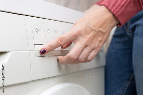 man presses the button on the washing machine