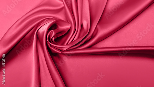 Viva Meganta toned red magenta fabric atlas. Close up pink silk satin texture for sewing. Abstract background wallpaper. Twisted folds cloth. Trendy color of the year 2023. Fashion color pattern