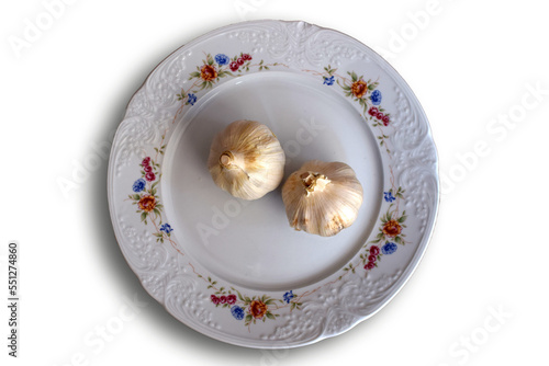 Dos cabezas de ajo en un plato blanco. 