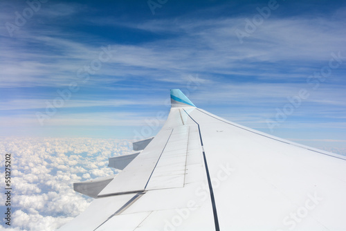 View from an airplane window showing the wing and sky with clouds