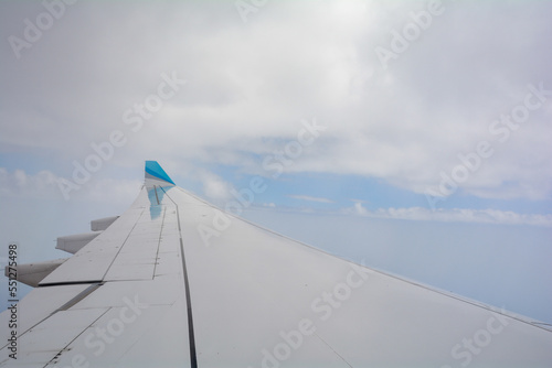 View from an airplane window showing the wing and sky with clouds © Claudia Evans 