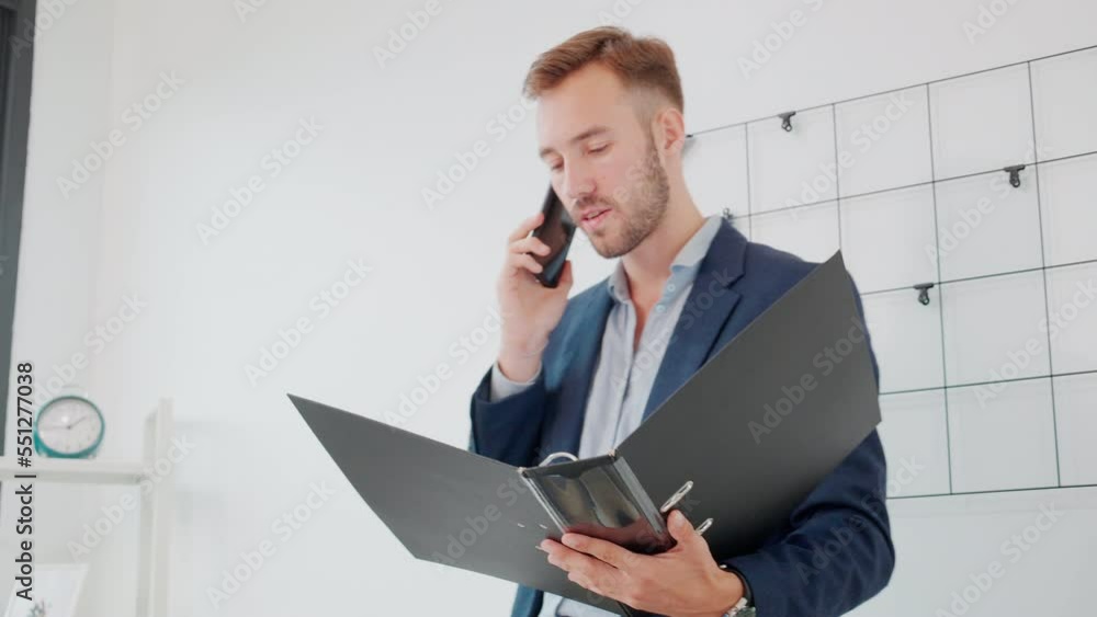 Young businessman looking to document in folder and talking on smart phone at the office, executive or manager looking report and information of finance, man or accountant, business concept. Young businessman looking to document in folder and talking on smart phone at the office, executive or manager looking report and information of finance, man or accountant, business concept.