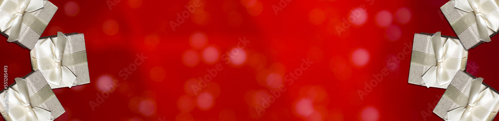 Christmas Gifts on the Glitter sparkling abstract red bokeh defocused background, border design panoramic banner. Christmas and New Year background. Christmas Gifts on the Glitter sparkling abstract red bokeh defocused background, border design panoramic banner. Christmas and New Year background.