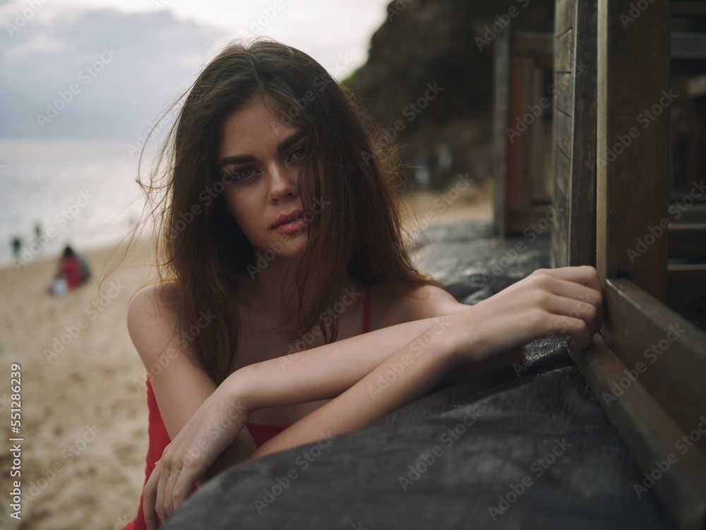 Young woman with a sad look looks into the camera portrait on the beach on a summer vacation trip to the sea