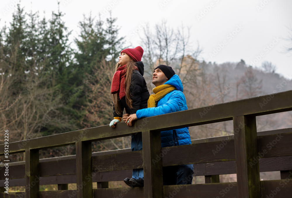 Man and his daughter walking in mountain in autumn, winter time, observing birds in national park. Parenthood. Father spends time with kid