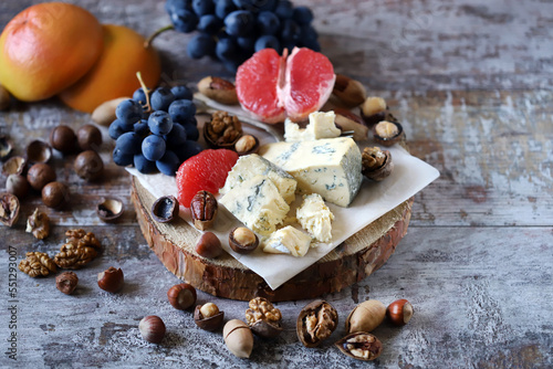 Cheeseboard. Cheese with nuts, grapefruit and grapes on a wooden board. Healthy snacks.