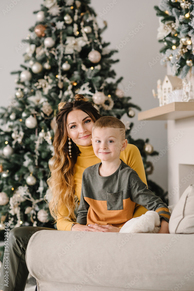 Mom hug son near Christmas tree. Happy New Year and Merry Christmas. Christmas decorated interior. The concept of family holiday. Close up.