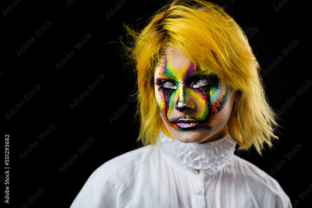 Portrait of woman in white shirt with yellow hair with evil clown face on black background