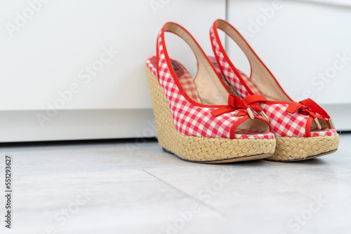 Red White open shoes with a high wedge heel in front of a closet