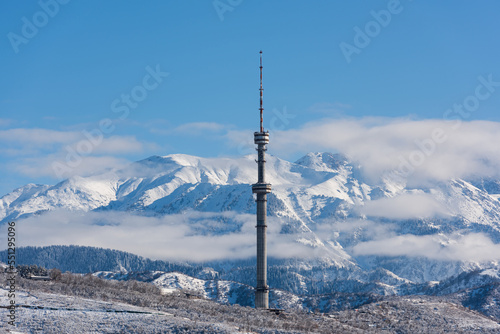 The famous TV tower in Almaty (Kazakhstan), located at an altitude of more than 1400 meters above sea level against the backdrop of snowy mountains photo