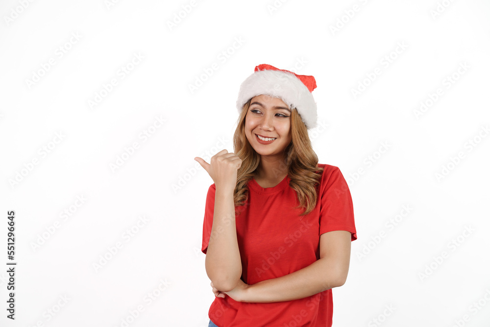 Happy asian woman in santa hat and red t-shirt isolated on white background. Pointing