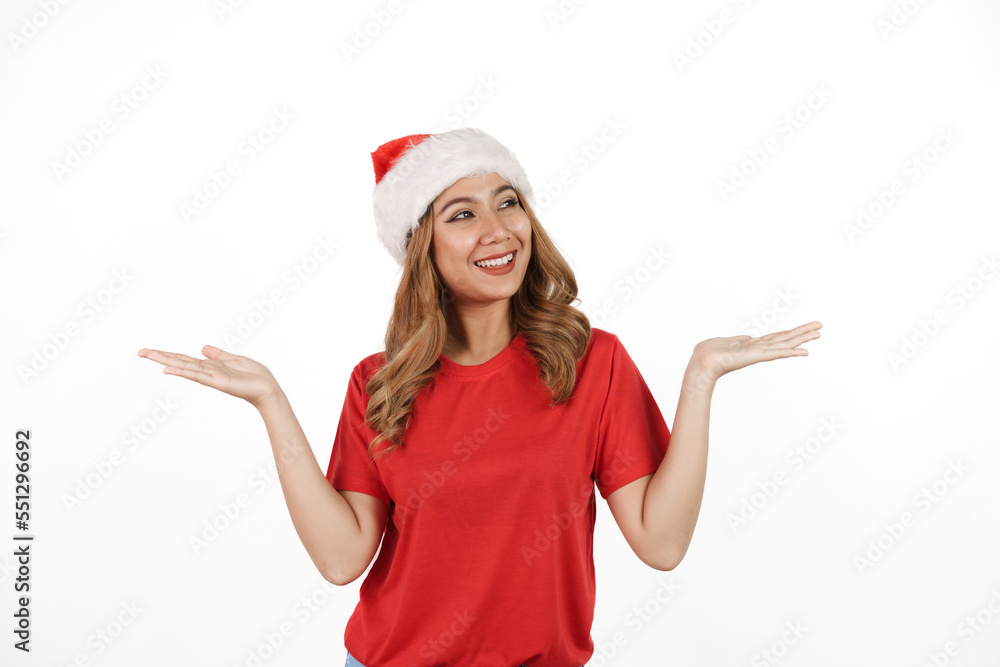 Happy asian woman in santa hat and red t-shirt isolated on white background. Palm up Happy asian woman in santa hat and red t-shirt isolated on white background. Palm up