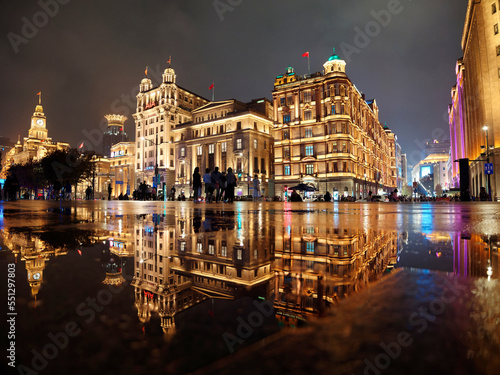 Shanghai bund landscape in rainy day, perfect reflection of historical building landmarks in puddles on sidewalks.