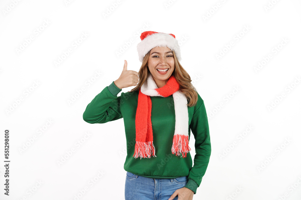 Attractive excited asian female in green sweater with santa hat on christmas isolated on white background. Thumb up Attractive excited asian female in green sweater with santa hat on christmas isolated on white background. Thumb up