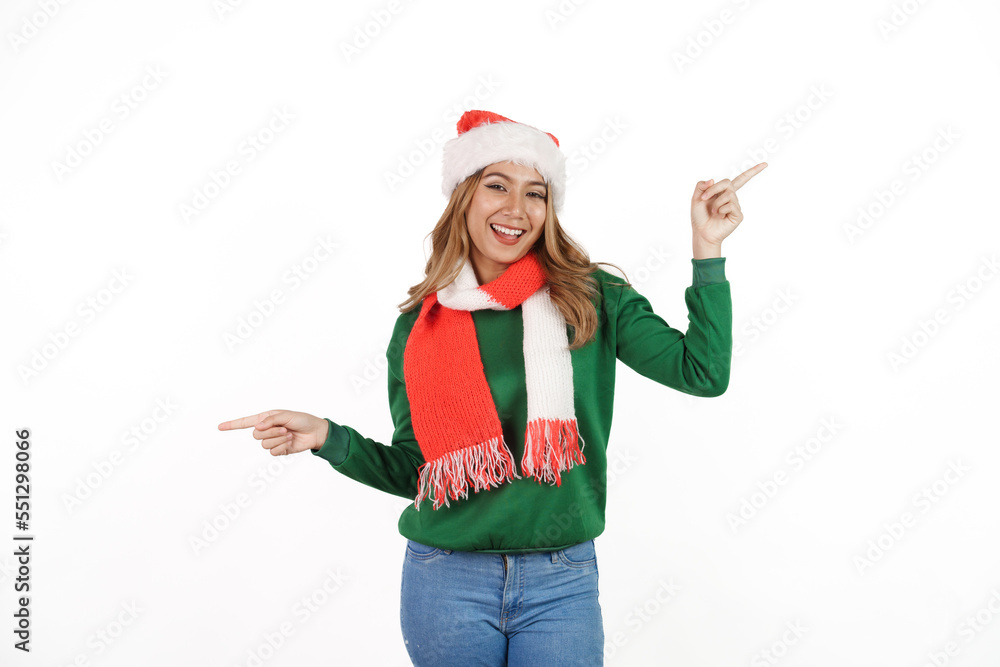Attractive excited asian female in green sweater with santa hat on christmas isolated on white background. Pointing hand Attractive excited asian female in green sweater with santa hat on christmas isolated on white background. Pointing hand