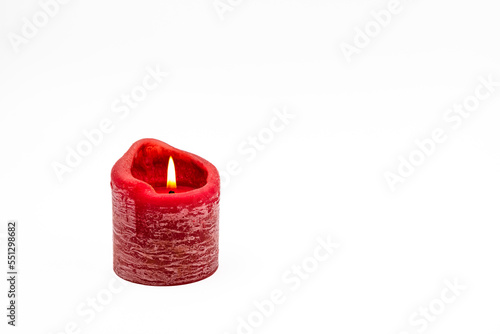 Eine rote brennende Kerze freigestellt vor weißem Hintergrund als Weihnachtskarte oder Grußkarte für Advent