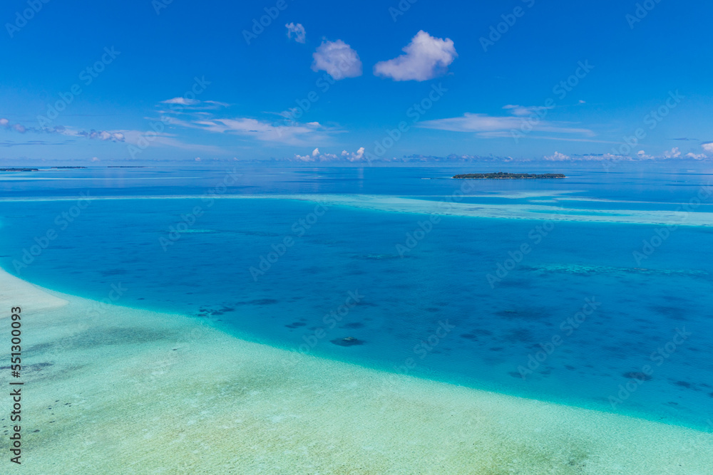 Aerial panorama of the blue lagoon bay in Maldives islands. Blue sea surface from above shallow ocean view. Horizon with sunny blue sky. Idyllic travel aerial seascape skyline. Tranquil blue wallpaper