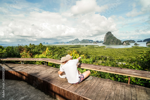 Happy traveler dad and son enjoying Phang Nga bay view point, Tourists relaxing at Samet Nang She in Southern Thailand. Summer vacation concept. photo