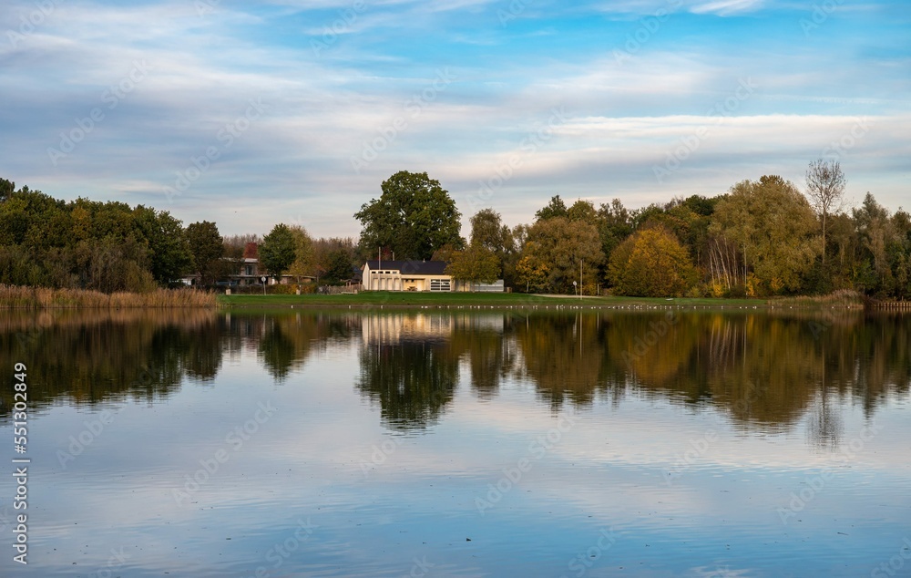 Rotselaar, Flemish Brabant Region, Belgium - Panoramic view over the De Plas water pond with reflecting trees in autumn colors Rotselaar, Flemish Brabant Region, Belgium - Panoramic view over the De Plas water pond with reflecting trees in autumn colors