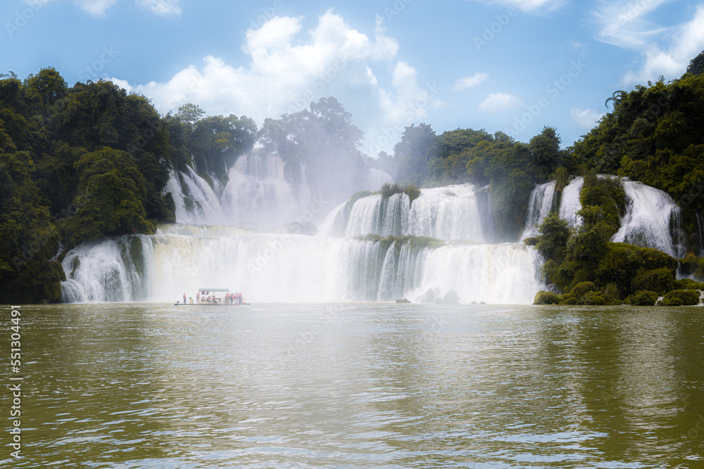 Fototapeta premium Ban Gioc Waterfall - Detian waterfall with a tourist boat, Ban Gioc Waterfall is the most magnificent waterfall in Vietnam, located in Dam Thuy Commune, Trung Khanh District, Cao Bang.