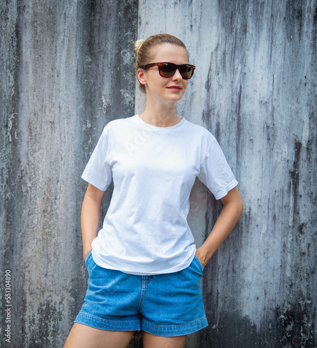 Female model wearing white blank t-shirt on the background of an gray scratched wall. © romaset