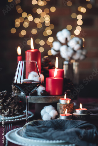 Rustic table decor for Christmas or New Year family dinner. Centrepiece with red candle, dry orange, cone, cinnamon, anise. Zero waste eco-friendly home. Cozy atmosphere, dark background. Close up