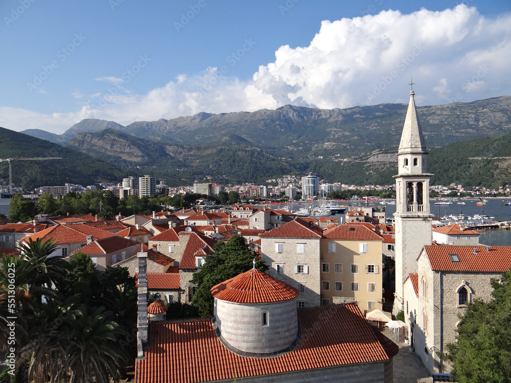 ancient town Budva in Montenegro with mountains, blue sky and clouds on background