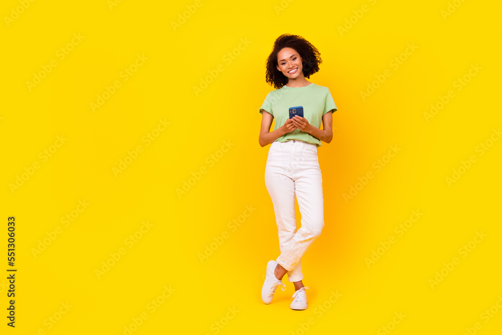 Full length photo of young pretty cute nice attractive woman toothy beaming hold phone youtube vlog much likes popular isolated on yellow color background