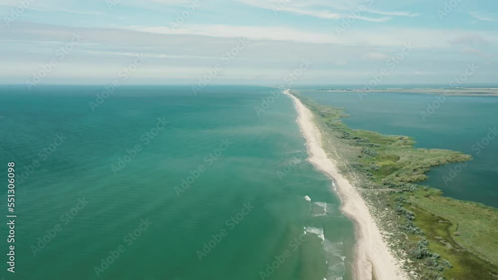 Aerial view of waves on a gritty ocean beach. Oncoming waves crashing against the sandy tropical shore over and over again. Aerial drone top view of sandy and wavy beach.
