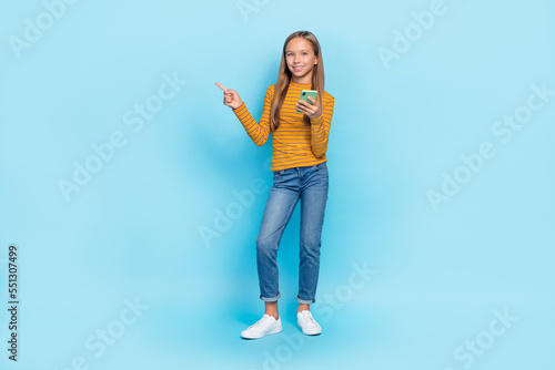 Full length portrait of positive cheerful girl hold telephone direct telephone empty space isolated on blue color background
