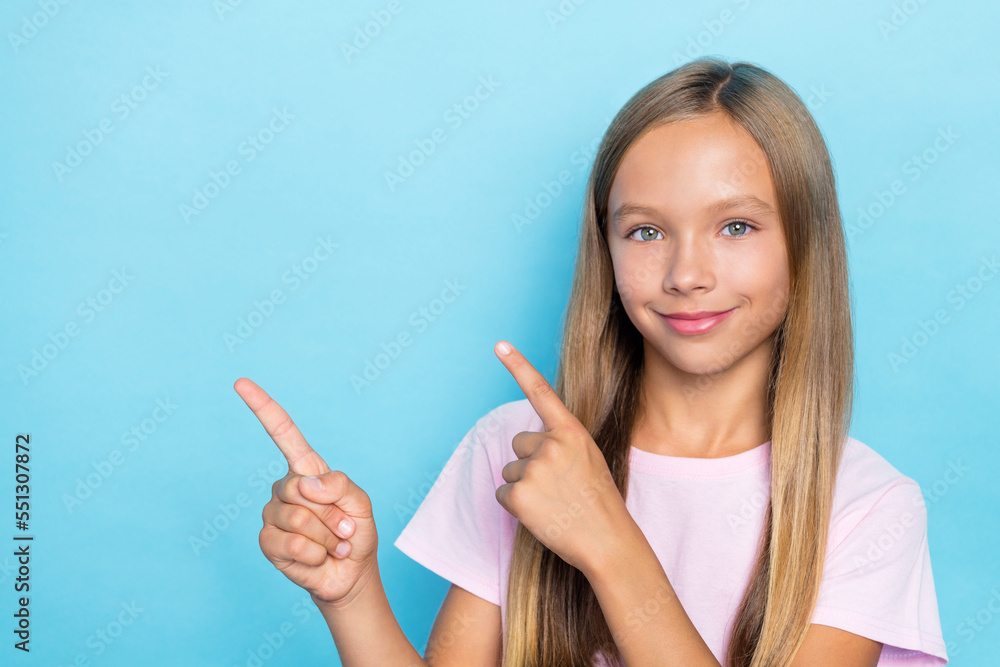 Portrait of good mood small girl straight hairstyle wear pink t-shirt fingers indicating empty space isolated on blue color background Portrait of good mood small girl straight hairstyle wear pink t-shirt fingers indicating empty space isolated on blue color background