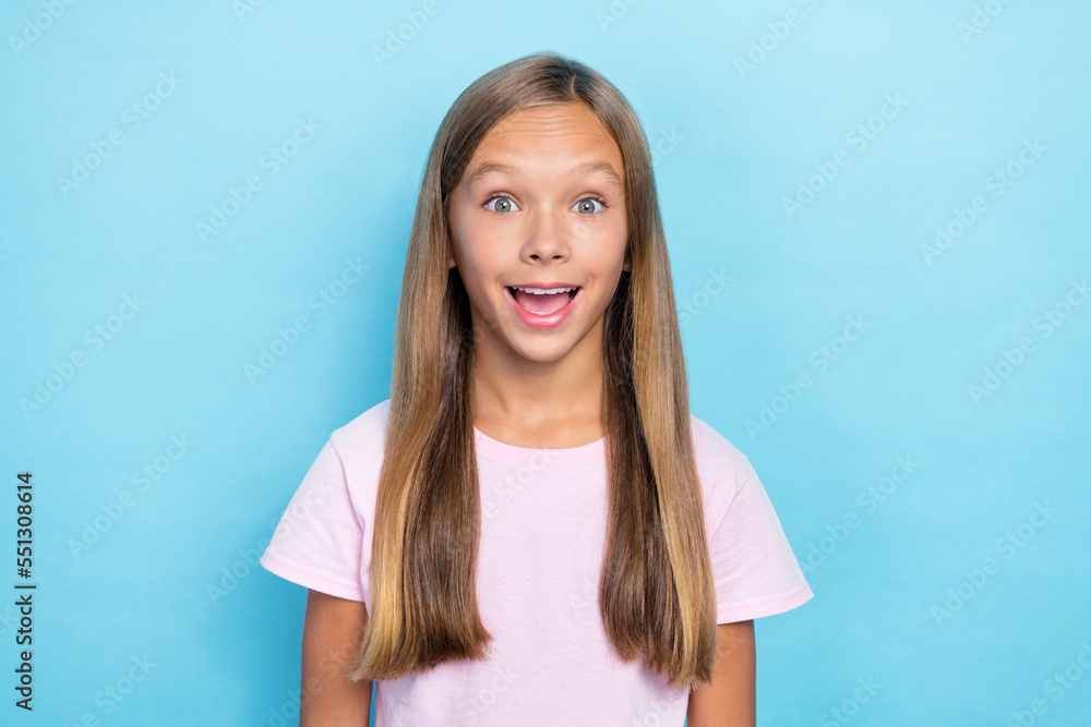 Fototapeta premium Portrait of cheerful impressed school girl with straight hairstyle wear pink t-shirt staring exited isolated on blue color background
