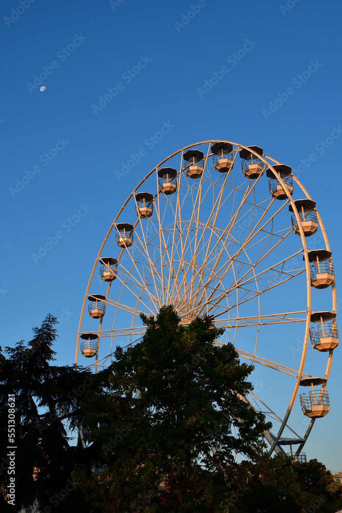 Fototapeta premium Switzerland, Geneva. Early morning moon and Ferris wheel. August 16, 2022.