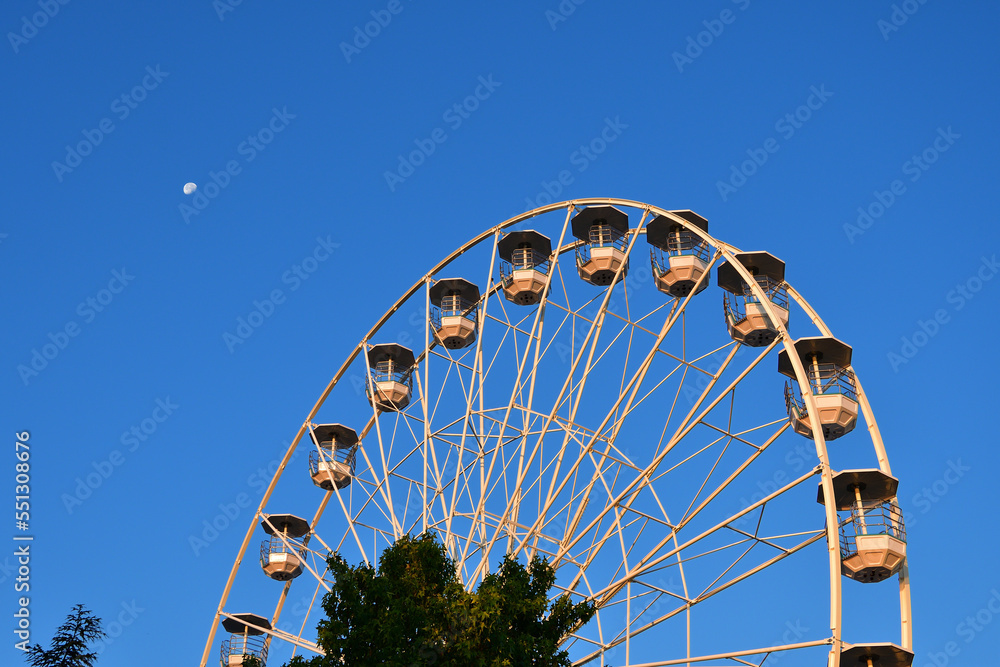 Fototapeta premium Switzerland, Geneva. Early morning moon and Ferris wheel. August 16, 2022.