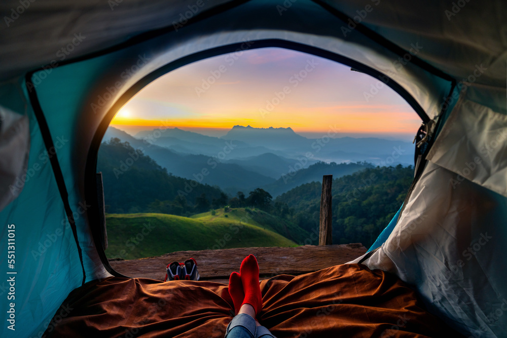 Woman cross leg on blanket in camping tent with sleeping bags on mountain hill. view from inside with Doi luang chiang dao mountains. - obrazy, fototapety, plakaty 