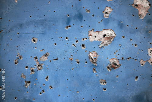 Holes from artillery shell fragments in the wall of an apartment building. Damage to a residential building as a result of artillery shelling. War in residential areas. Armed conflict in Ukraine
