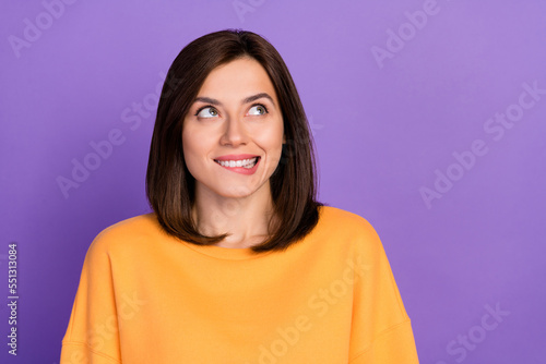 Closeup photo of young pretty gorgeous adorable lady wear orange sweater excited bite lips nervous dreamy look empty space isolated on violet color background