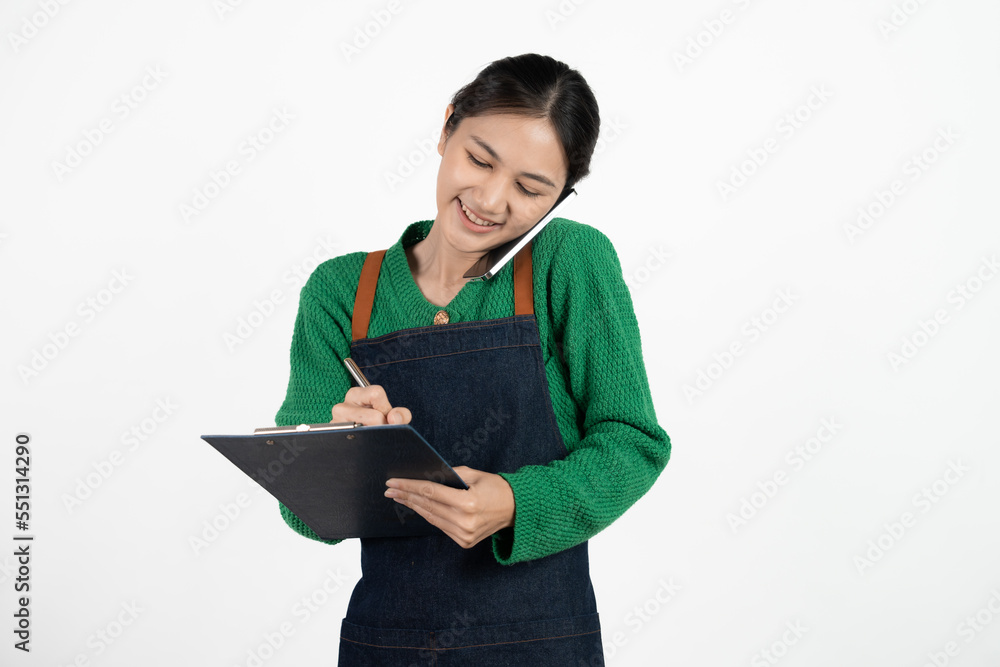 Portrait of smiling mature woman in apron holding clipboard. Beautiful waitress isolated on white background with copy space. Successful small business owner standing on white background. Portrait of smiling mature woman in apron holding clipboard. Beautiful waitress isolated on white background with copy space. Successful small business owner standing on white background.