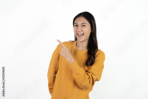 Young beautiful Asian businesswoman smiling and pointing to empty copy space isolated on white background.