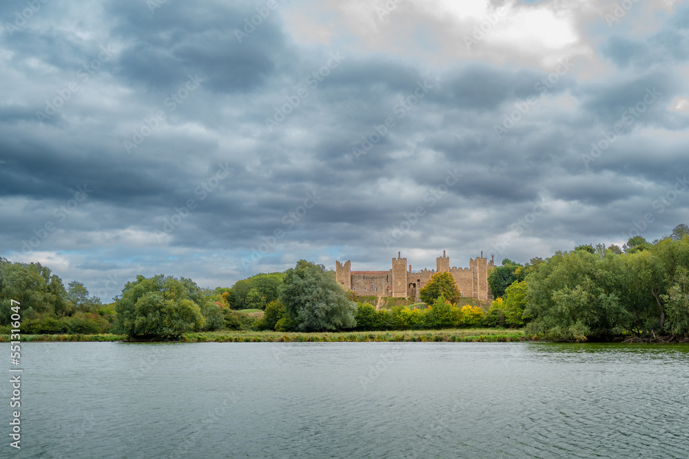 Distant view of a English castle seen across a large lake. Menacing skies appear before the start of a storm. Distant view of a English castle seen across a large lake. Menacing skies appear before the start of a storm.