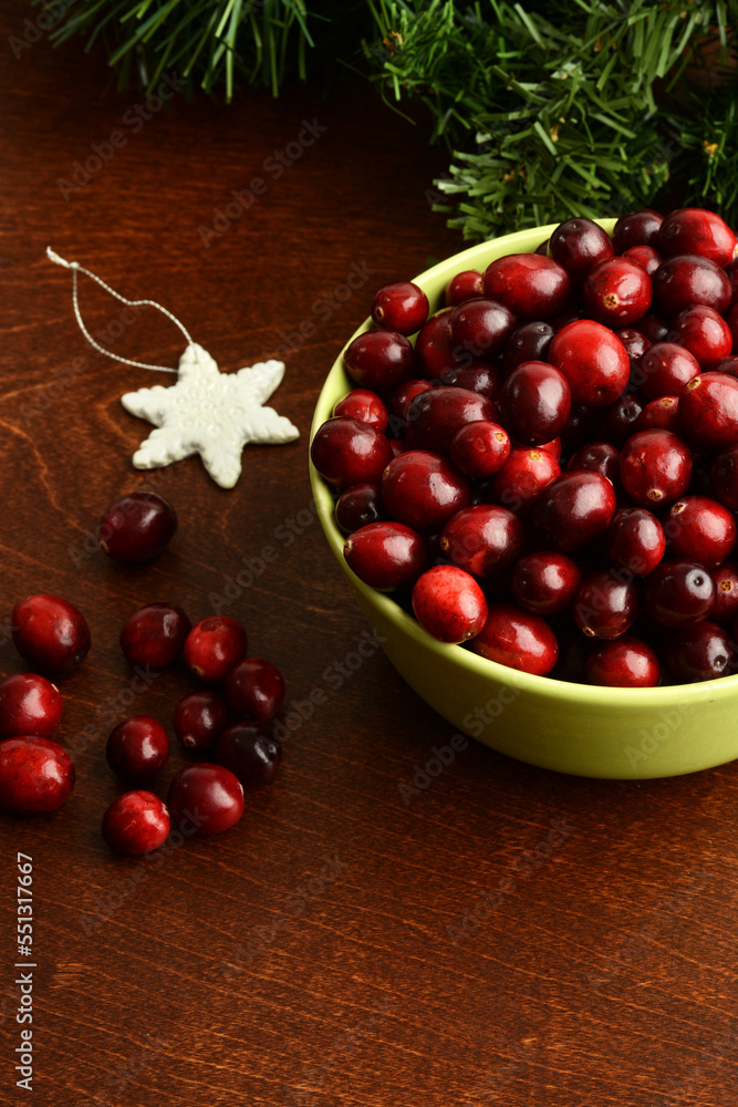 green bowl of cranberries with snowflake ornament on wood table green bowl of cranberries with snowflake ornament on wood table