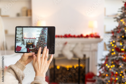 Holding digital tablet in cozy living room with fireplace on background. smart home app