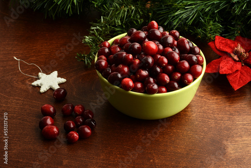 green bowl of fresh cranberries at christmas time with poinsettia flower