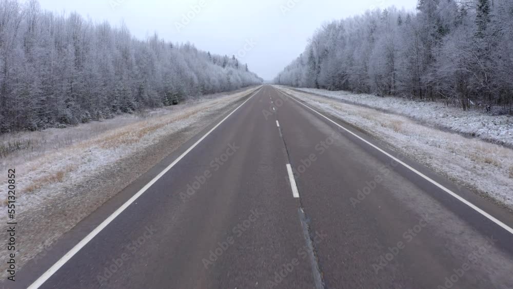 Drone flight along the road markings in the forest covered with snow. Flying close to the median strip Drone flight along the road markings in the forest covered with snow. Flying close to the median strip